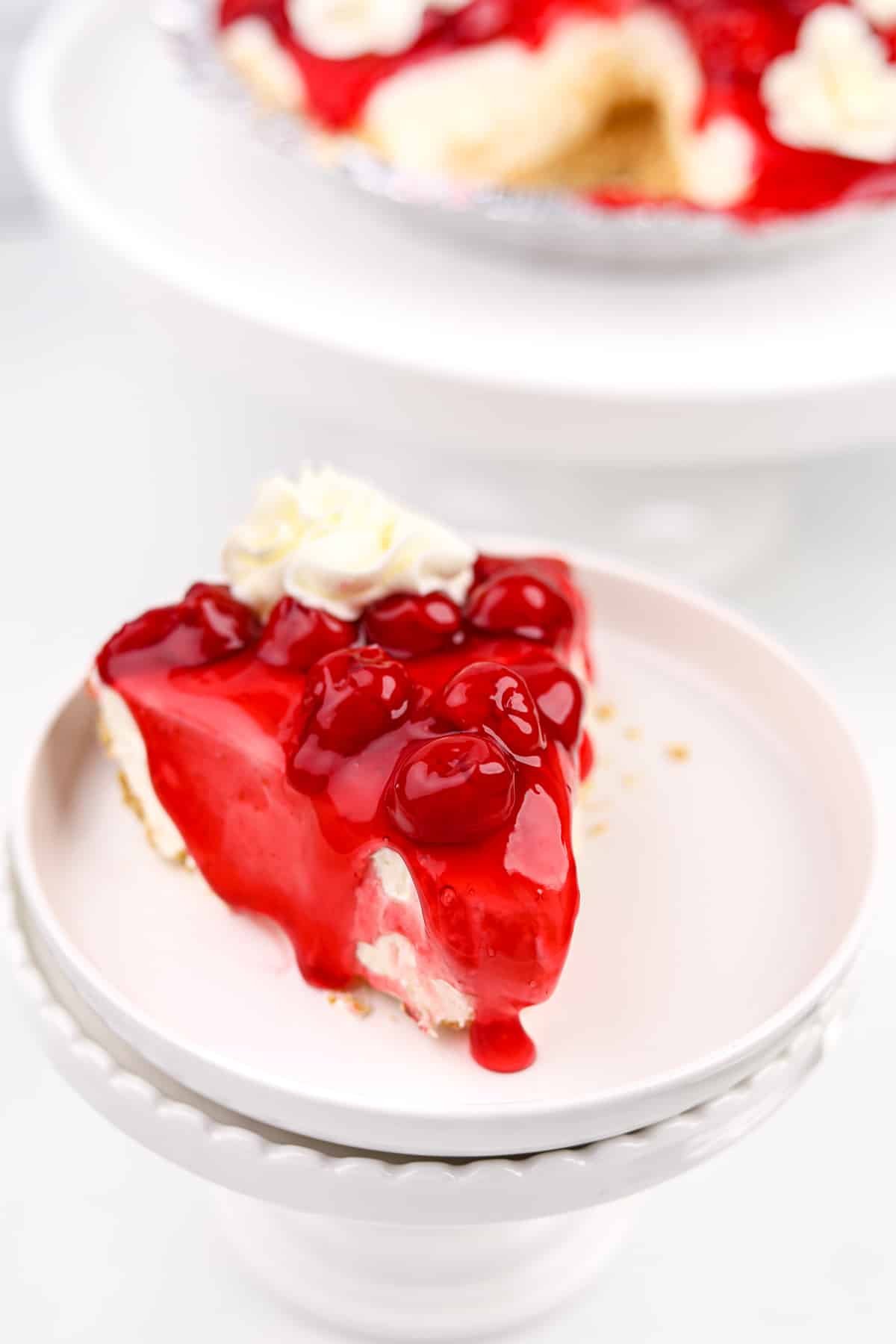 A slice of cheesecake topped with cherries and a glaze.
