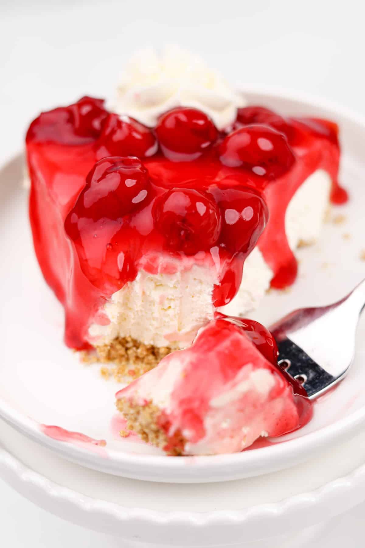A close up of a slice of cheesecake pie topped with a cherry glaze.
