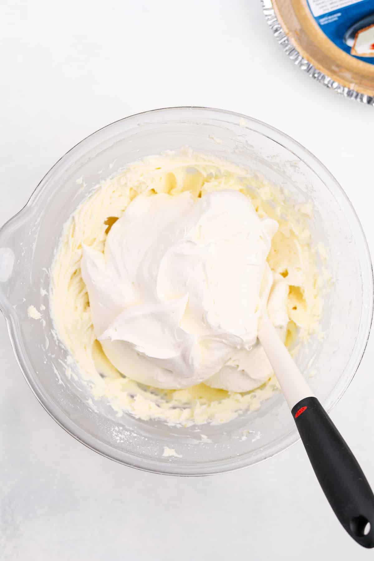 Adding thawed whipped topping to a cream cheese filling.