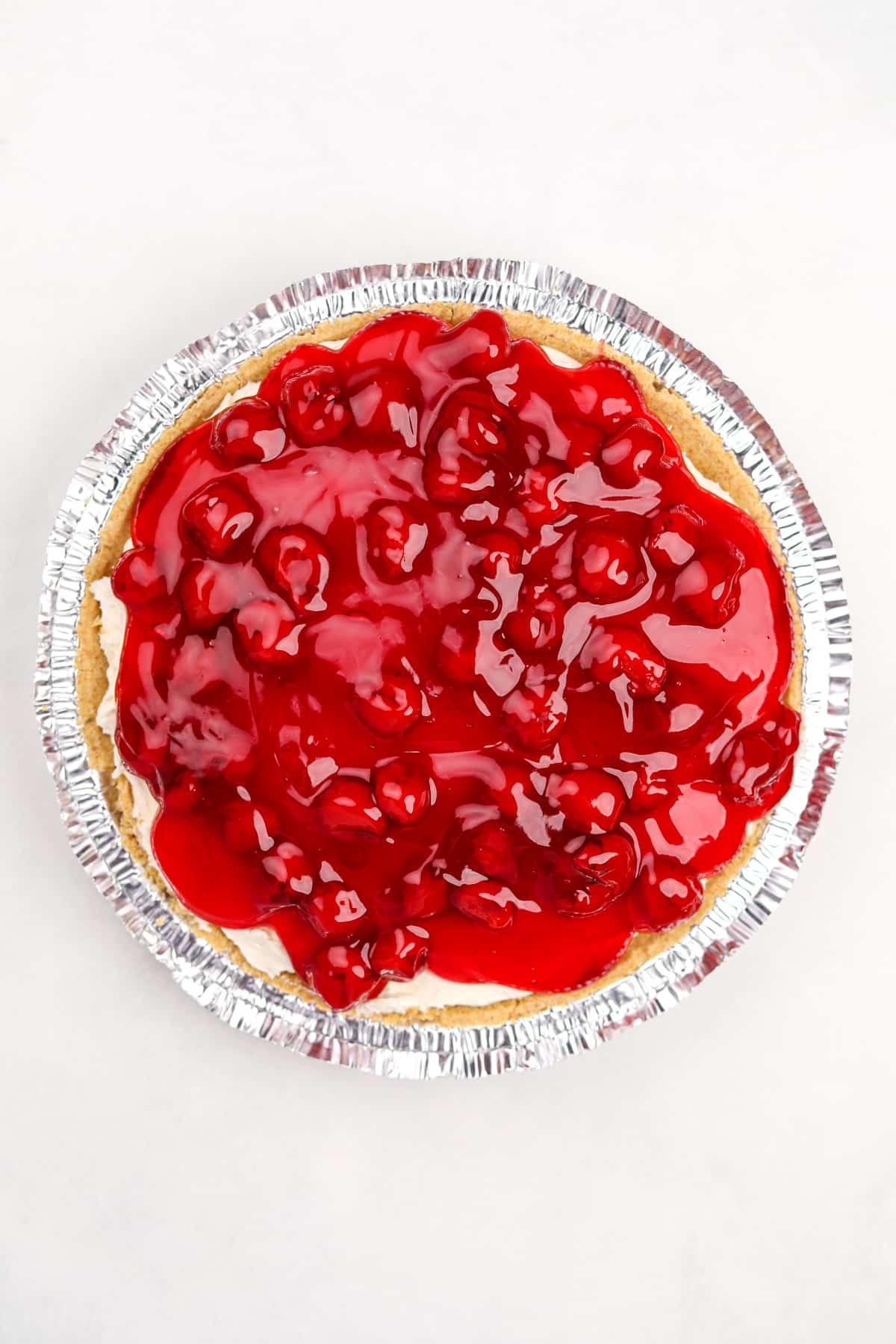 A cheesecake pie topped with cherry pie filling.
