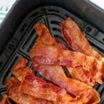 An air fryer basket filled with cooked crispy bacon. The text reads: "air fryer perfect crispy bacon"