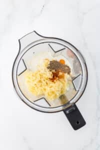 A blender filled with eggs, cottage cheese, seasonings, and shredded cheese.