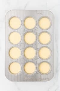 A muffin pan with all of the wells filled with an egg mixture.
