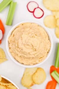 A bowl of onion dip, with fresh veggies and potato chips