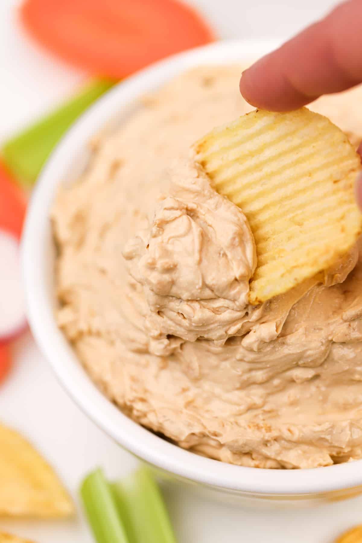 Dipping a potato chip into french onion dip.