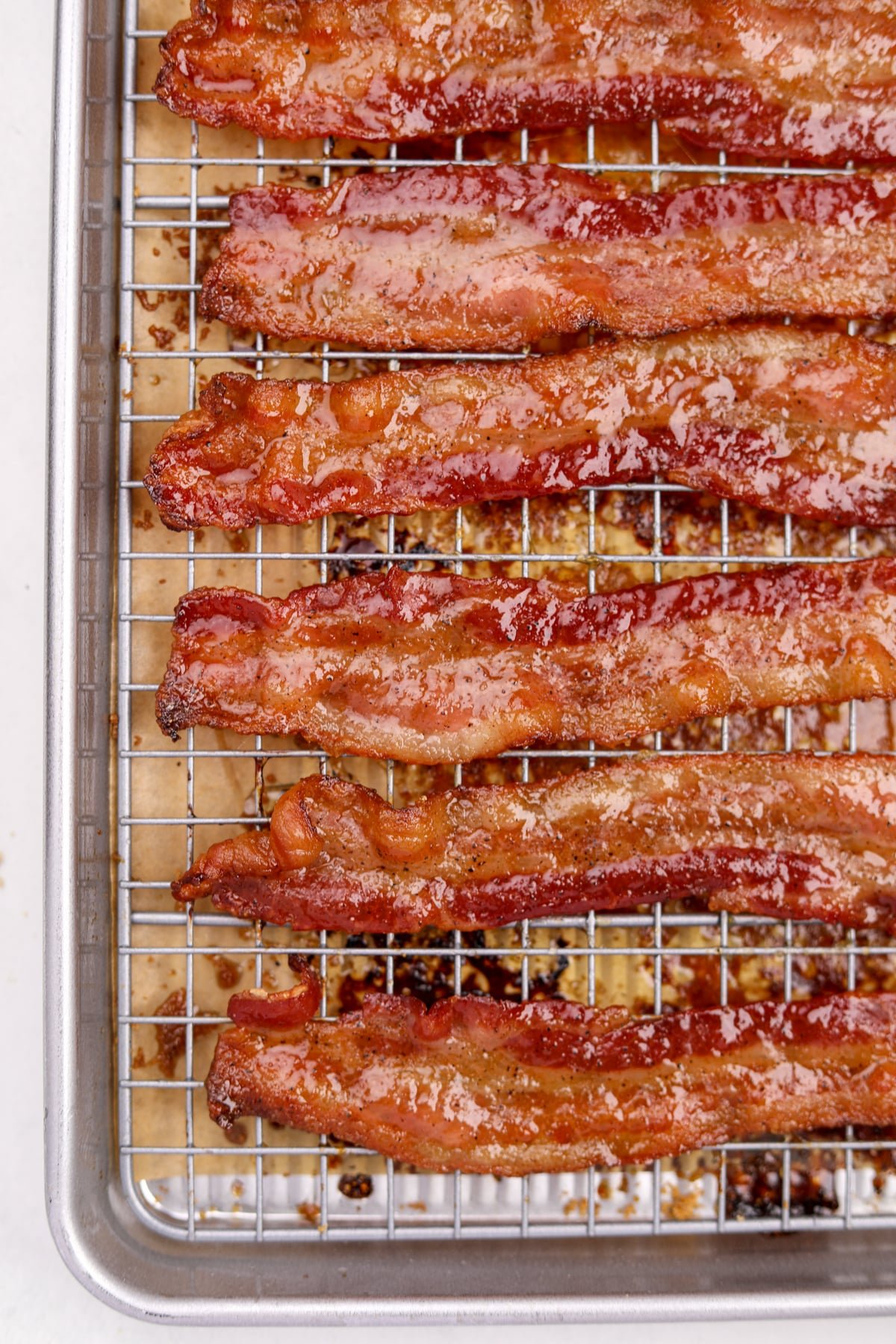 A wire baking rack filled with glazed bacon slices.