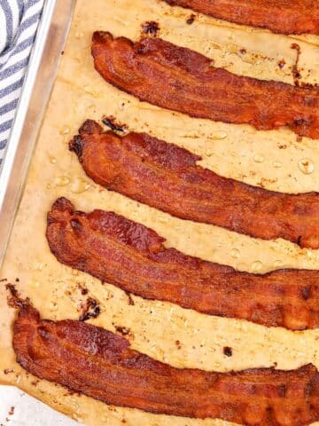 Slices of crispy bacon on a parchment lined baking sheet.