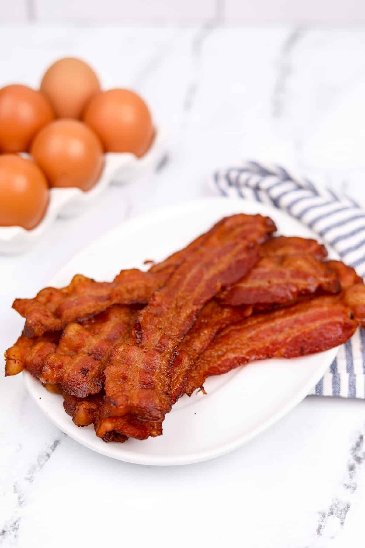 A white plate piled high with crispy bacon pieces.