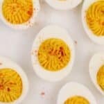 Deviled egg halves on a grey background, sprinkled with paprika.