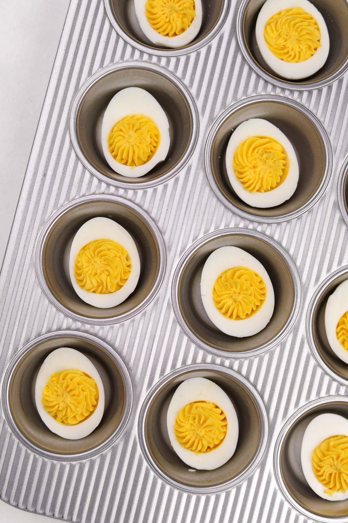 A muffin pan with a deviled egg in each well.