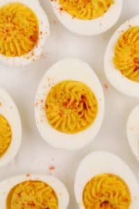 Deviled eggs on a grey background, sprinkled with paprika.