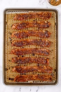A baking sheet filled with cooked bacon that's crispy and coated with brown sugar.