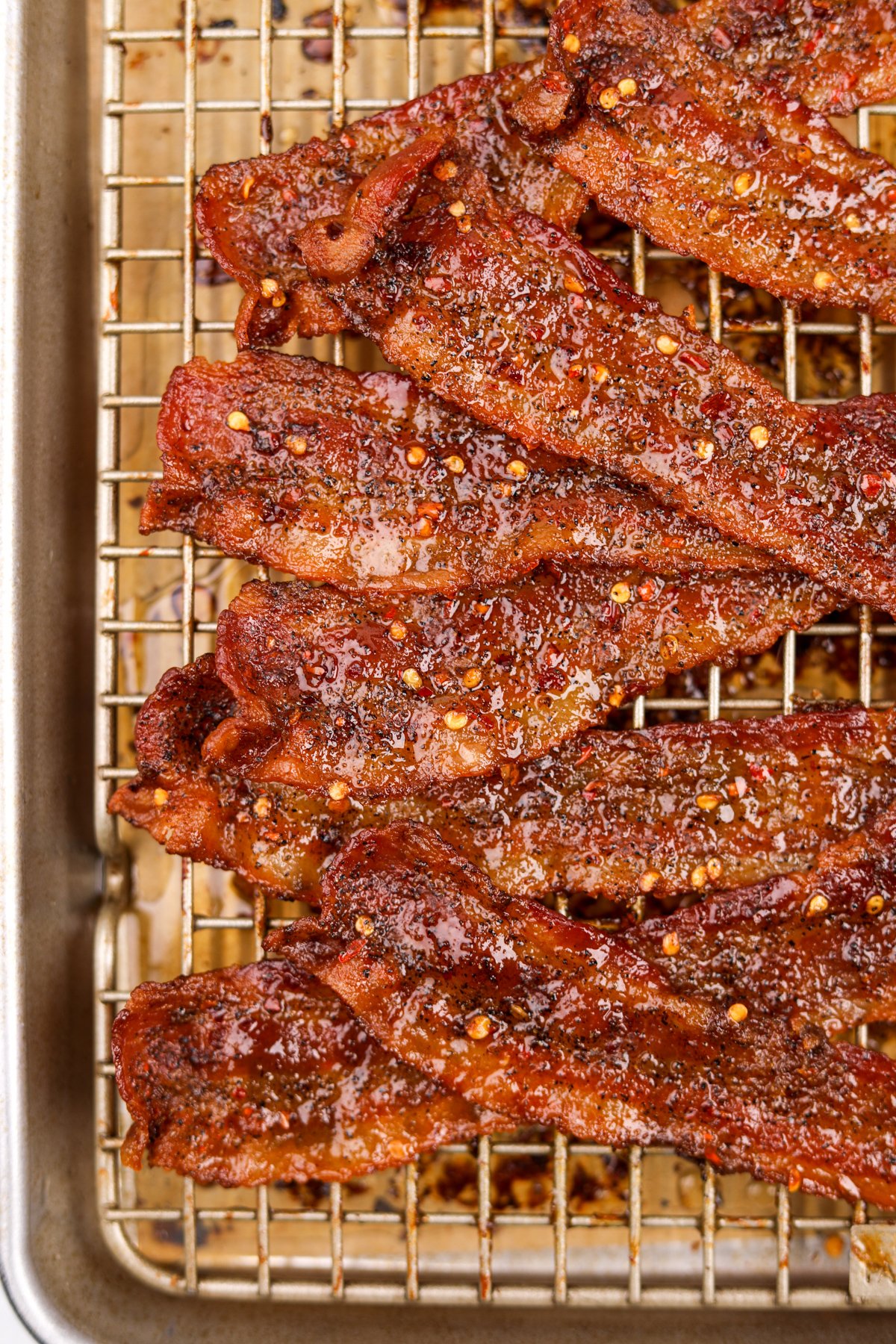 Bacon that has been candied with brown sugar and is stacked on a wire baking rack.