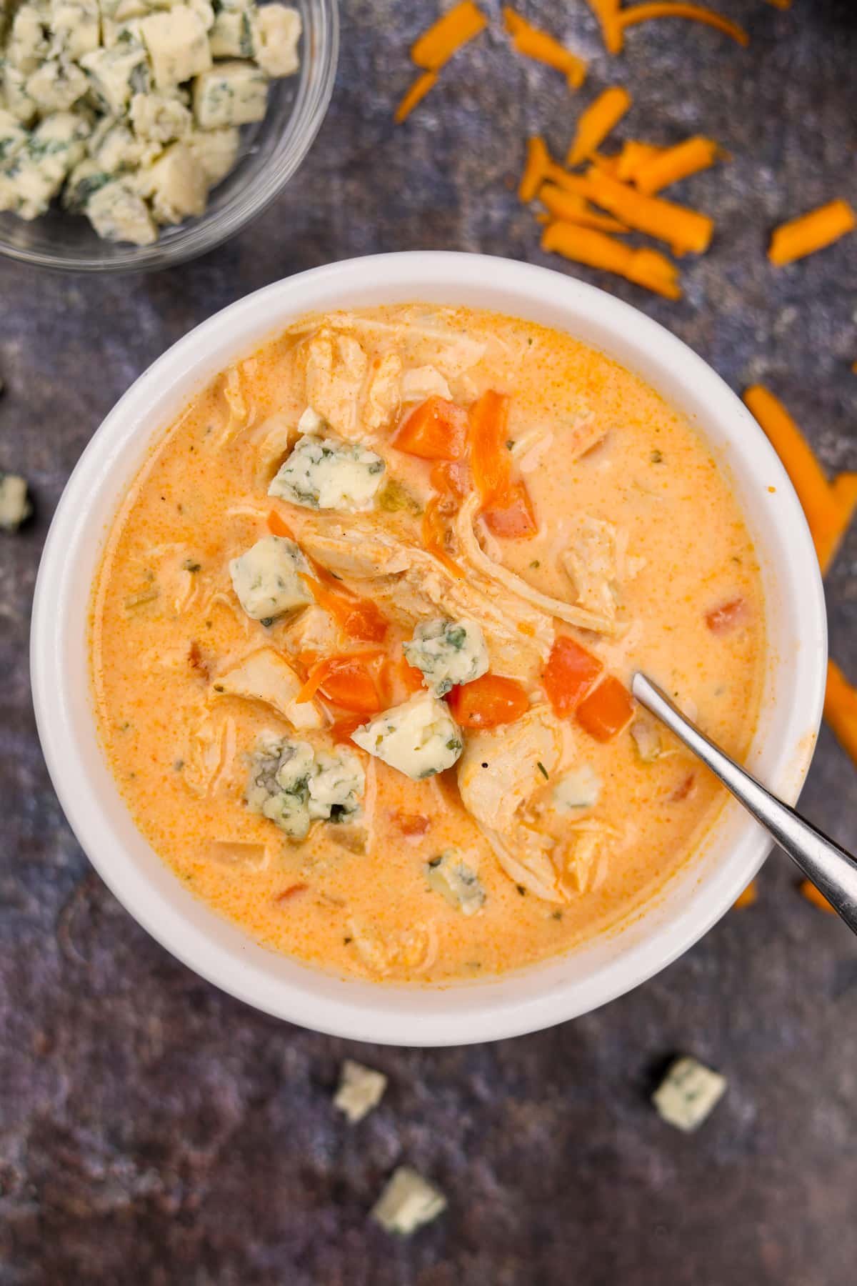 A bowl of buffalo chicken soup topped with blue cheese crumbles.