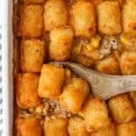 A baking dish filled with a casserole that is topped with Tater Tots.