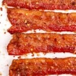 Slices of bacon dotted with red pepper flakes and glazed with brown sugar.