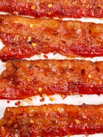 Slices of bacon dotted with red pepper flakes and glazed with brown sugar.
