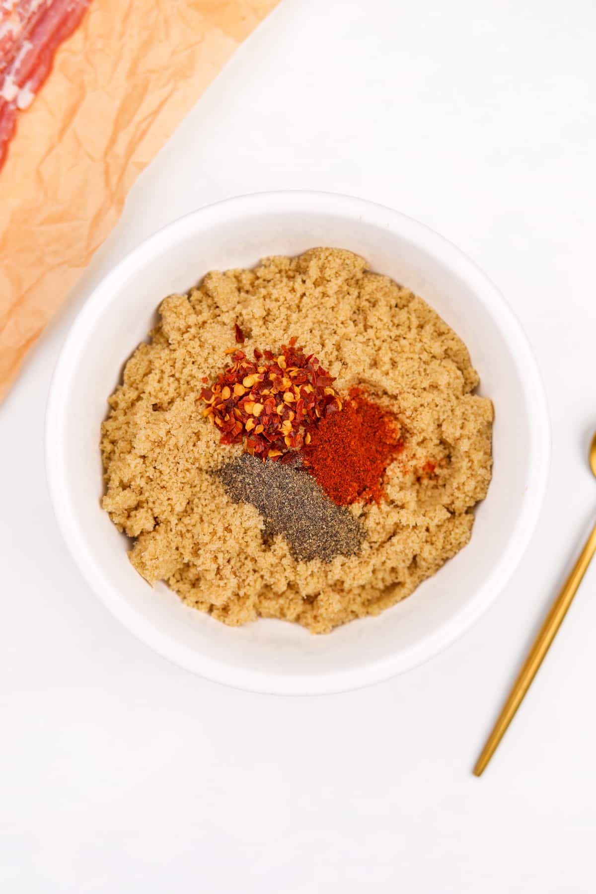 A bowl of brown sugar with cayenne, pepper, and red pepper on top.