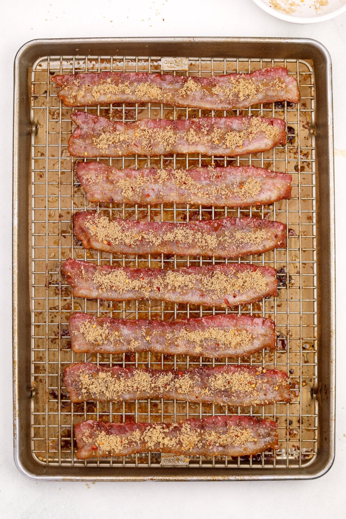 Bacon on a baking sheet topped with brown sugar.