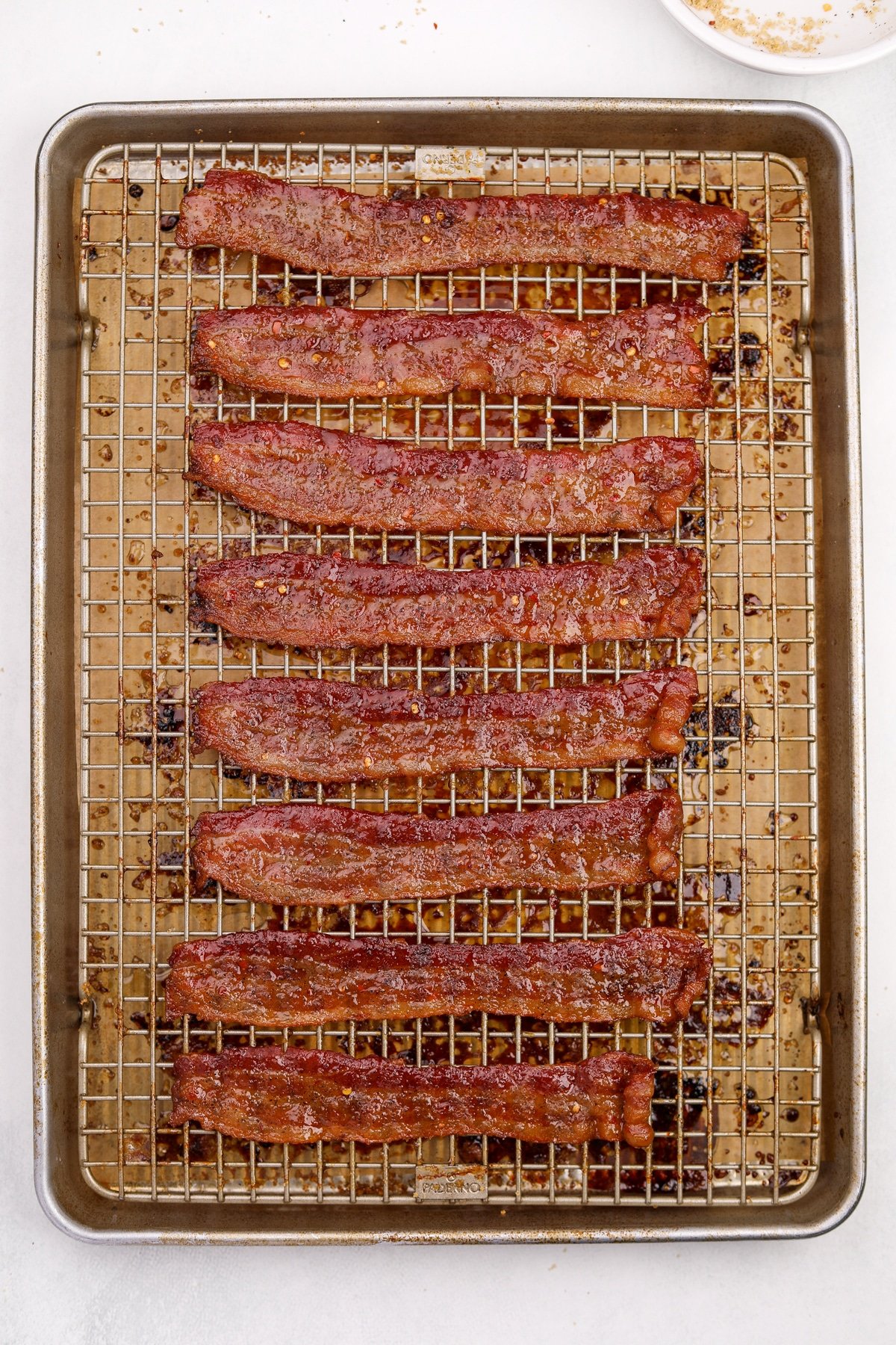 Cooked and candied bacon on a baking sheet.