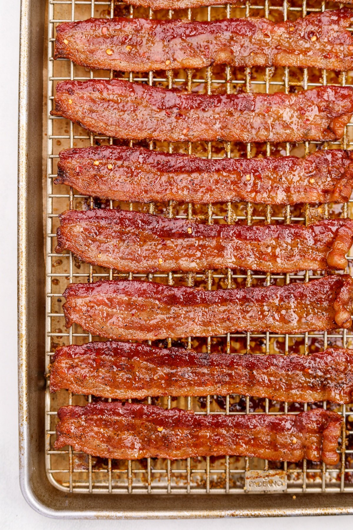 A baking sheet filled with cooked and candied bacon slices.