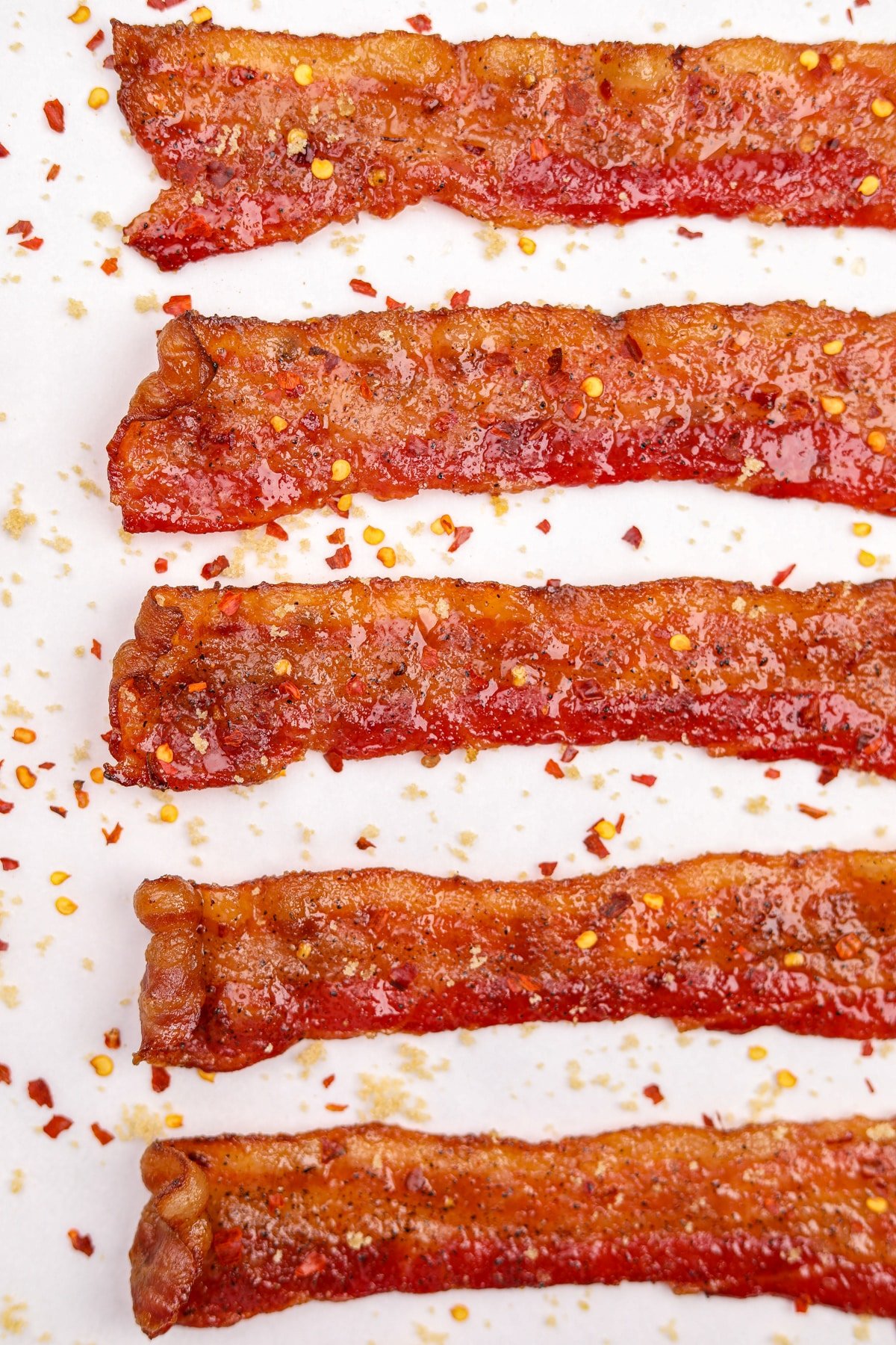 Slices of cooked and candied bacon on a white background.