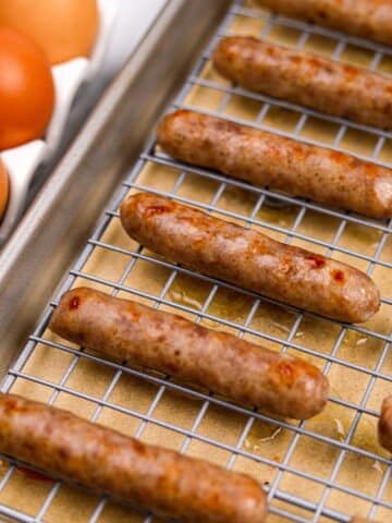 A baking sheet with cooked breakfast sausages lined up.