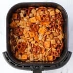 An air fryer basket filled with Chex mix.