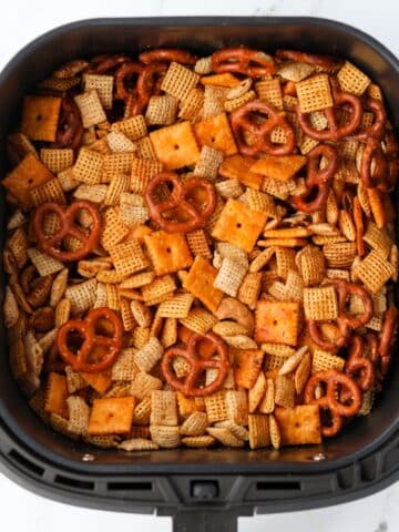 An air fryer basket filled with Chex mix.