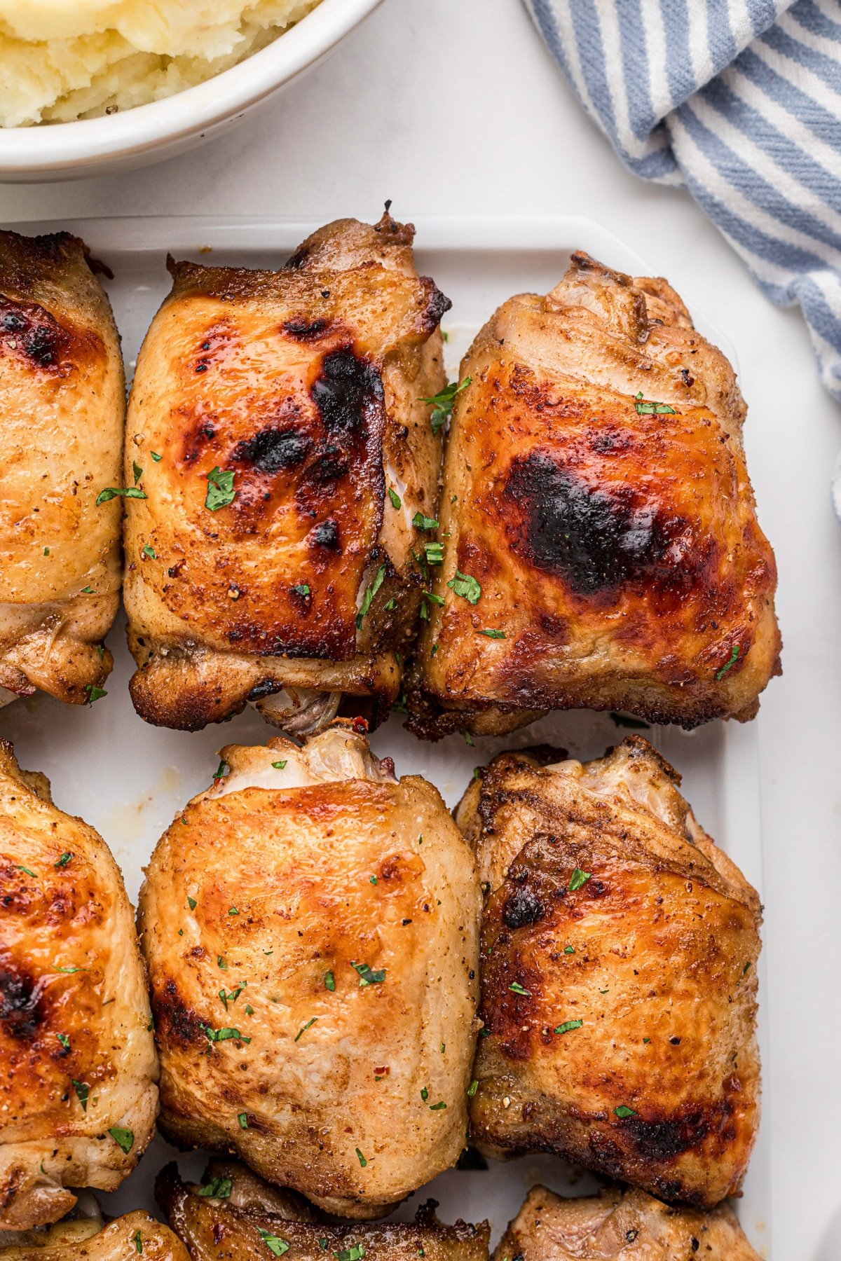 Crisp chicken thighs on a white serving tray.