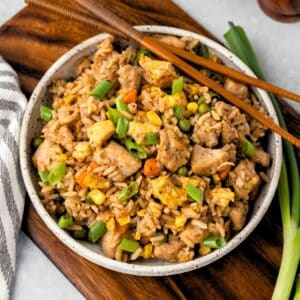 A bowl of chicken fried rice with chopsticks on the side.