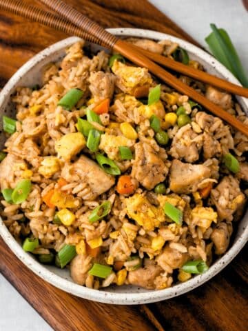 A bowl of chicken fried rice with chopsticks on the side.