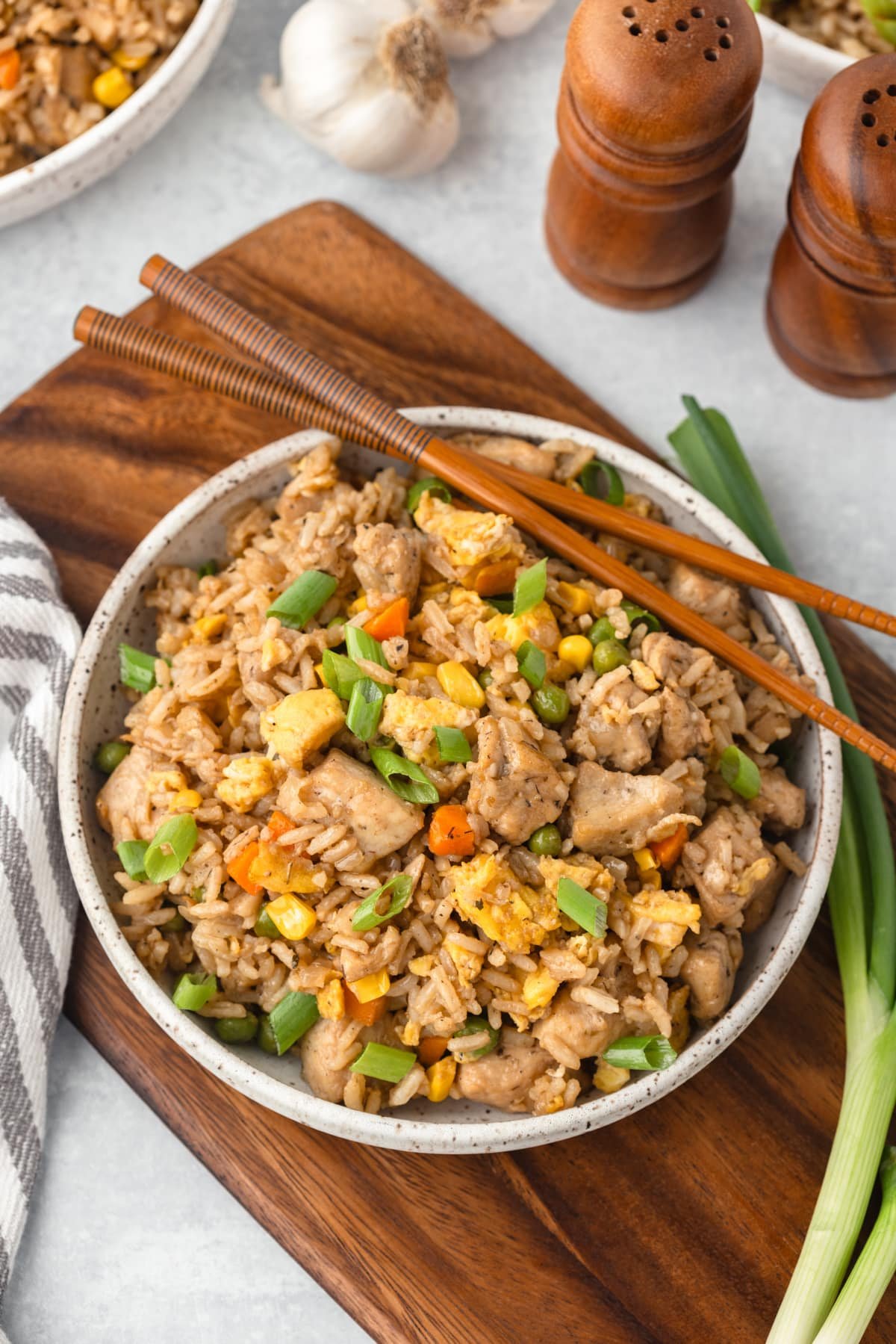 A bowl of chicken fried rice with a pair of chopsticks on the side.