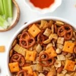 A white bowl filled with homemade snack mix featuring pretzels, nuts, and more!