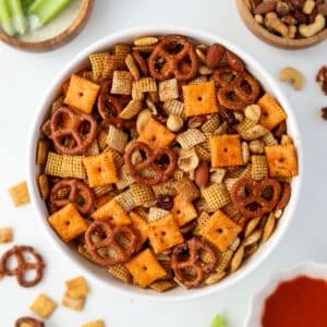 A white bowl filled with Chex Mix, dotted with pretzels, crackers, and nuts.