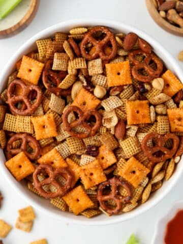 A white bowl filled with Chex Mix, dotted with pretzels, crackers, and nuts.