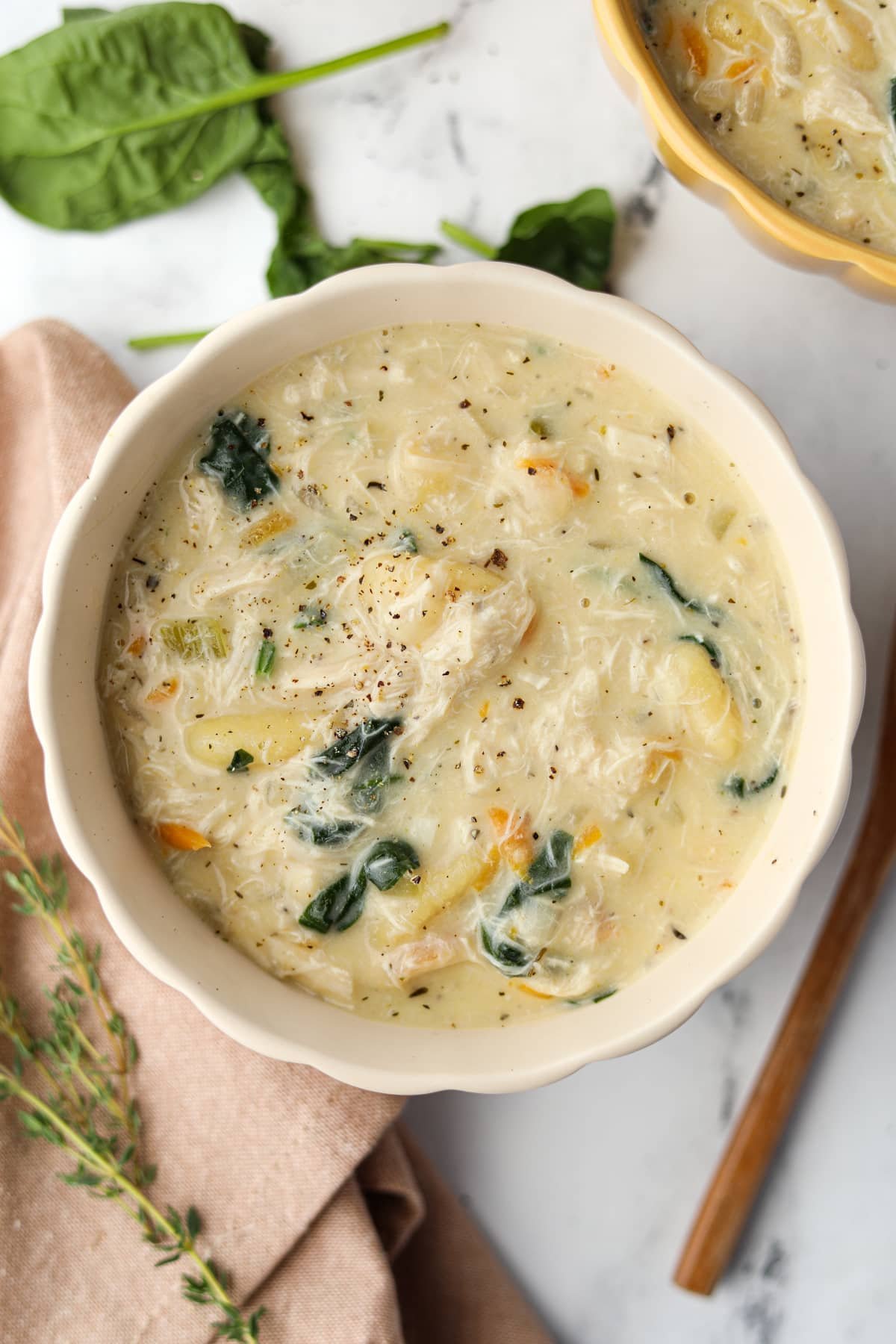 A bowl of creamy soup with gnocchi and spinach.