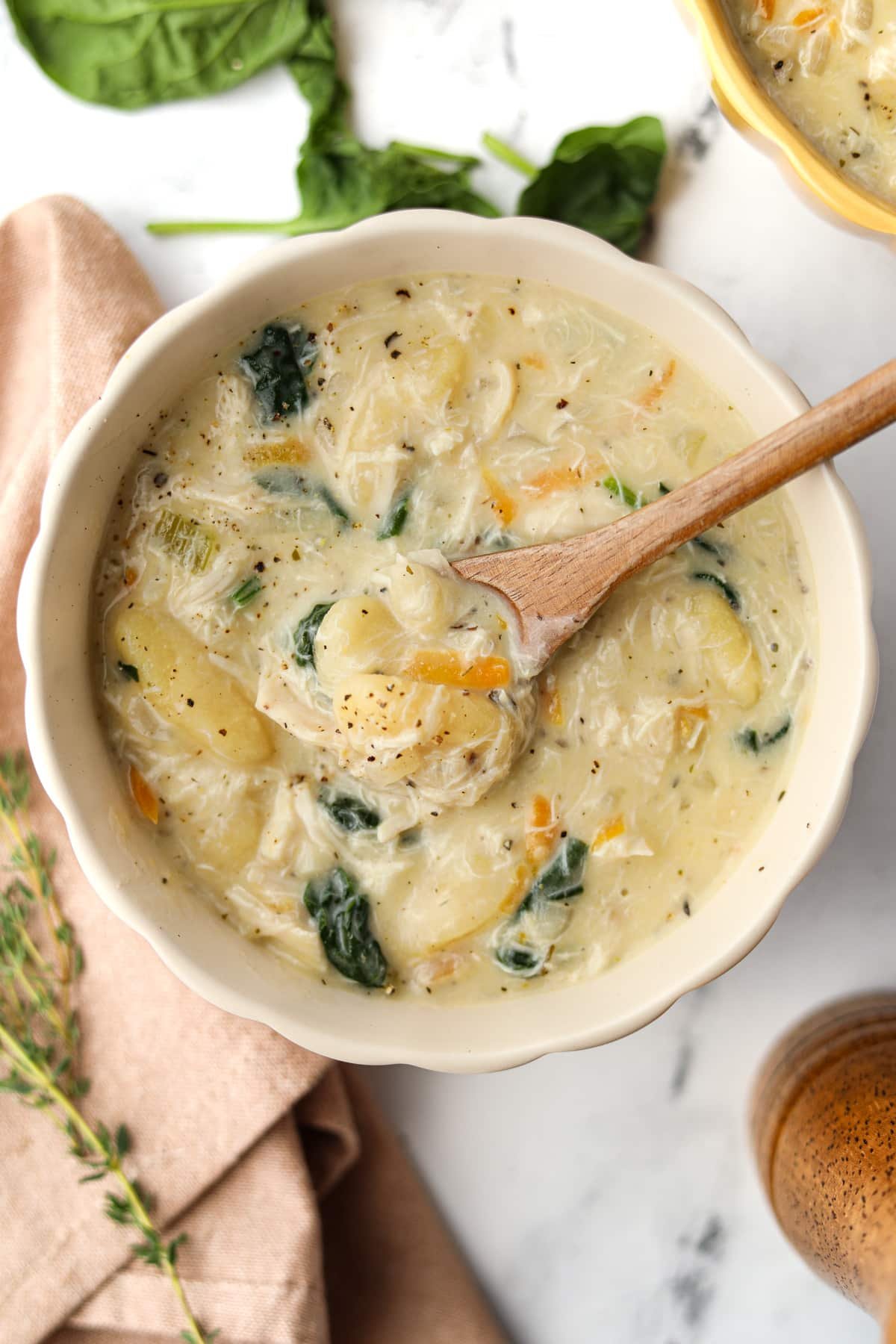 A bowl of chicken soup with a small wooden spoon inside.