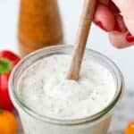 Stirring ranch dressing with a wooden spoon in a Weck jar.