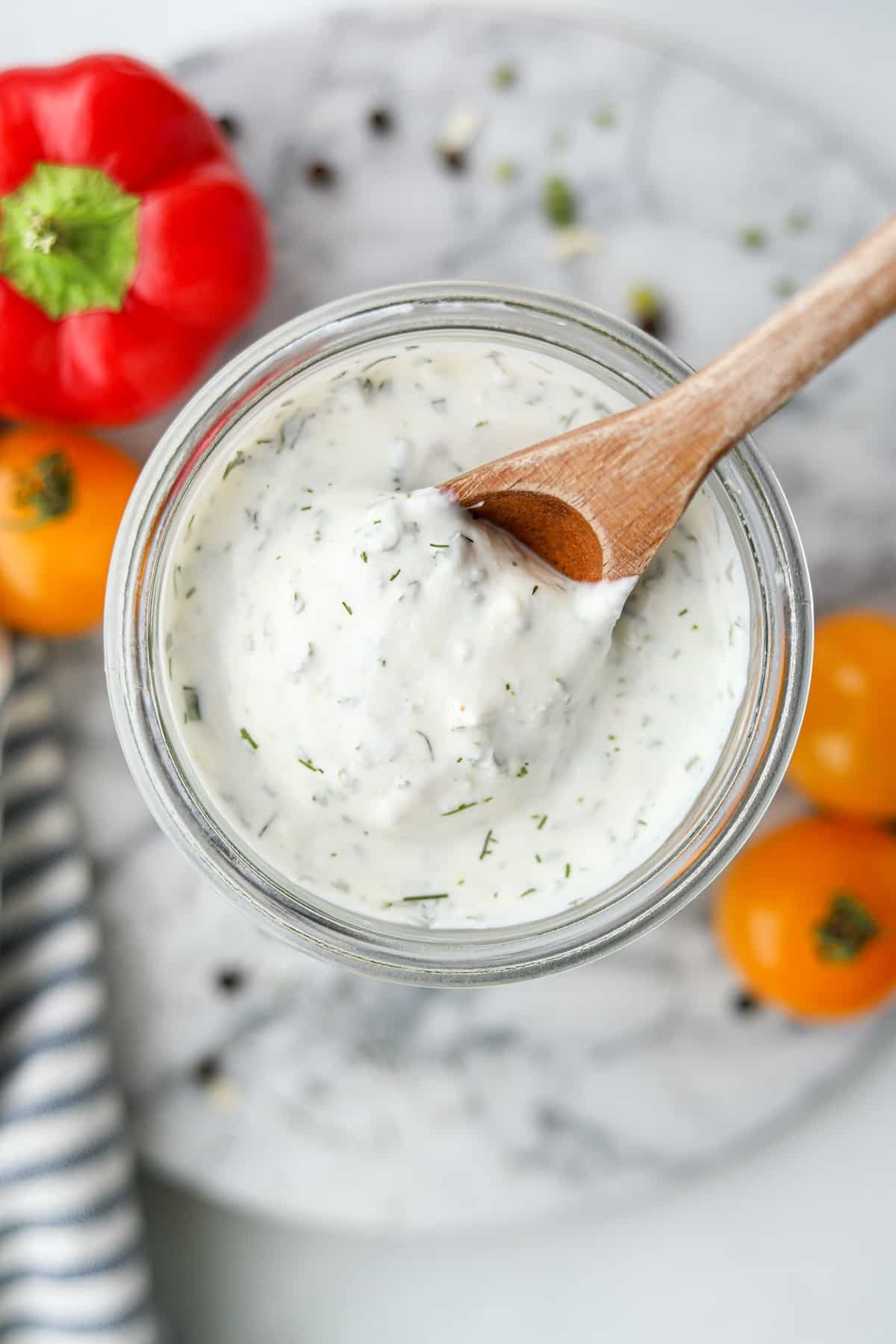 Scooping ranch from a glass jar with a wooden spoon.