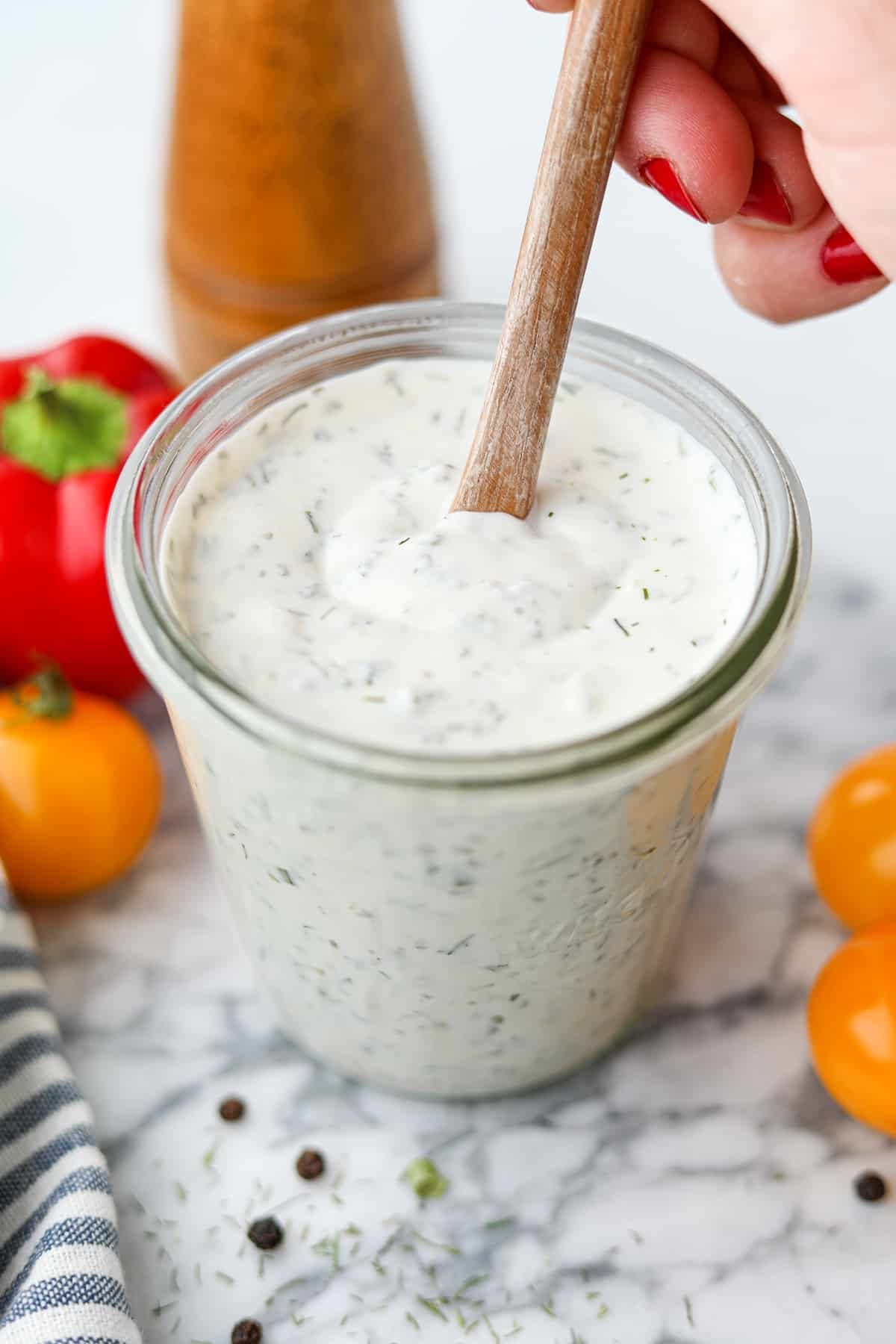 Stirring ranch dressing in a glass jar.