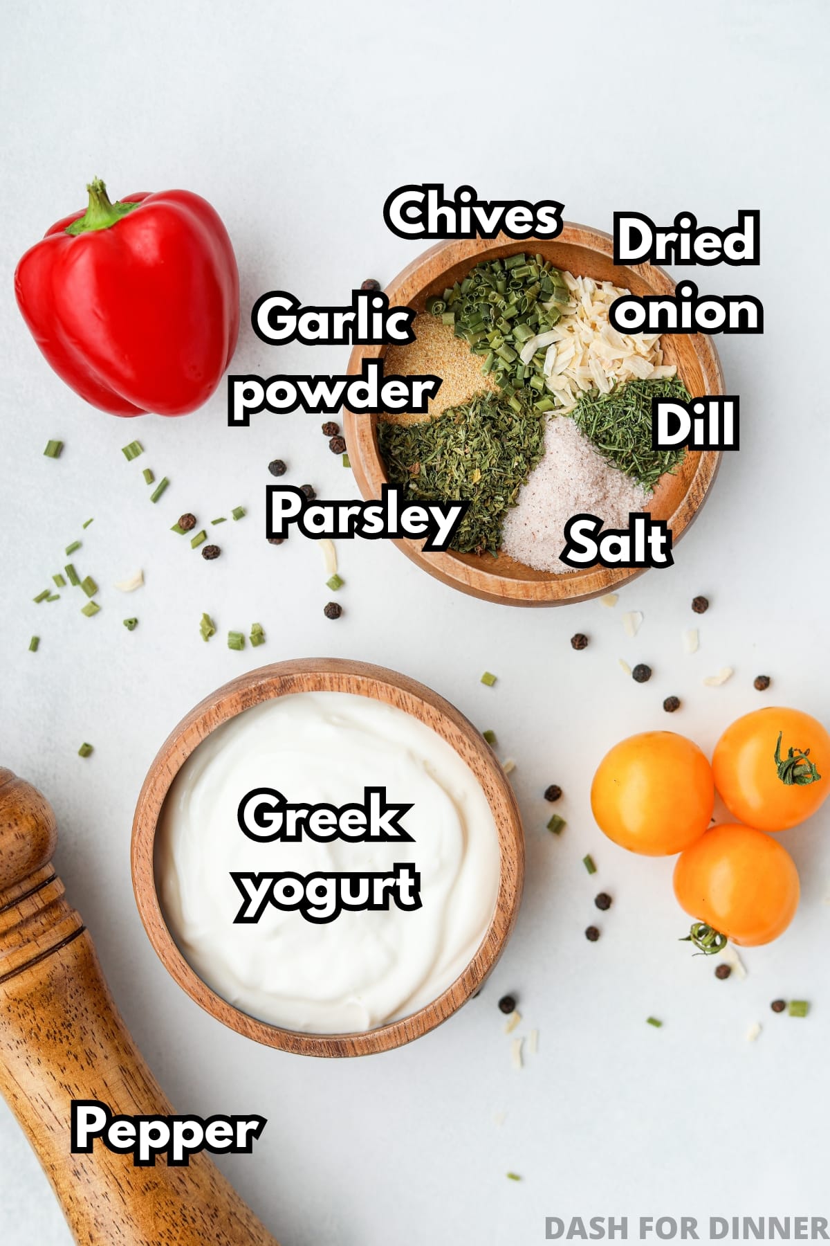 A small bowl of greek yogurt, and another small bowl filled with various seasonings (chives, dill, parsley, salt, etc).