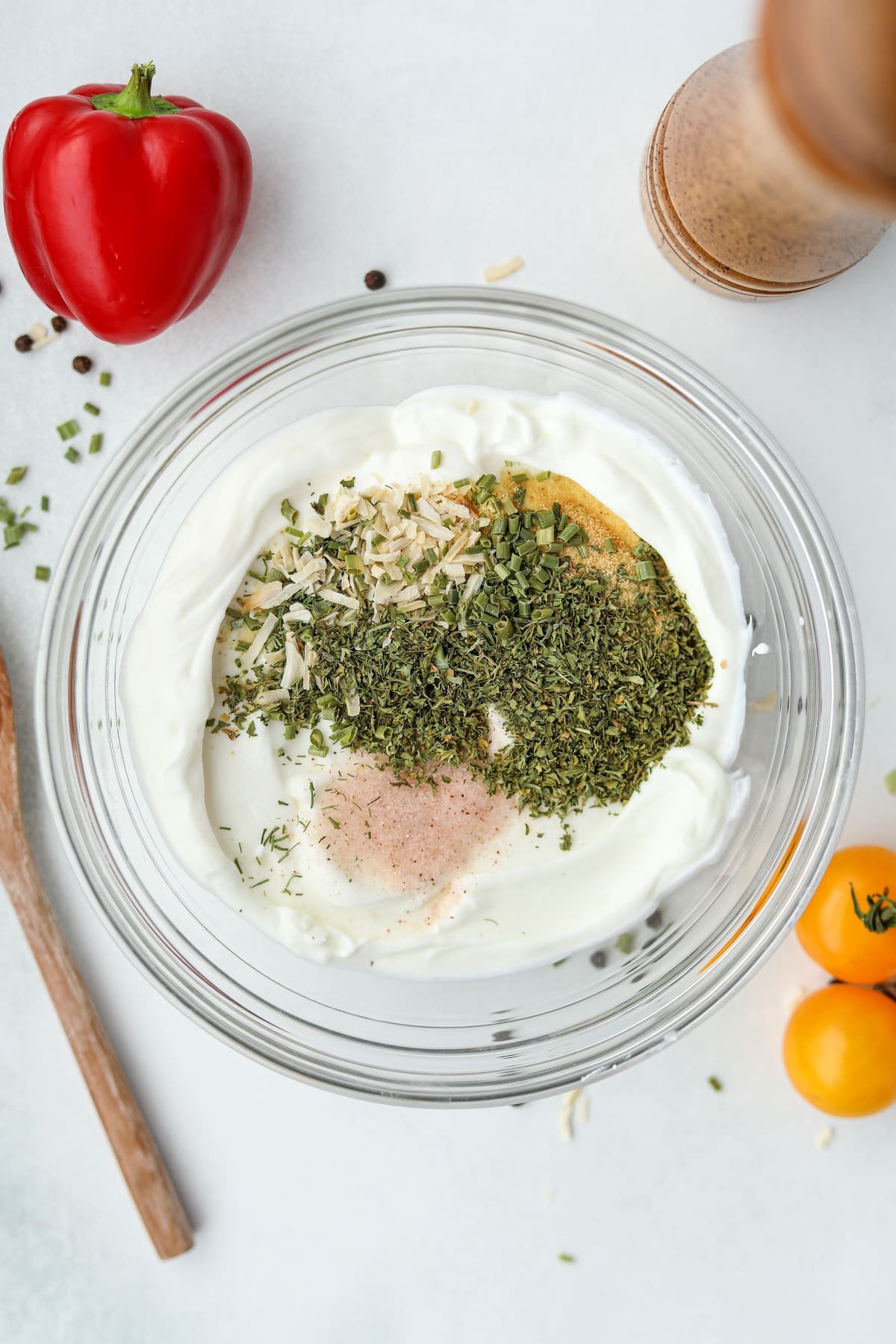 A bowl of greek yogurt filled with various seasonings.