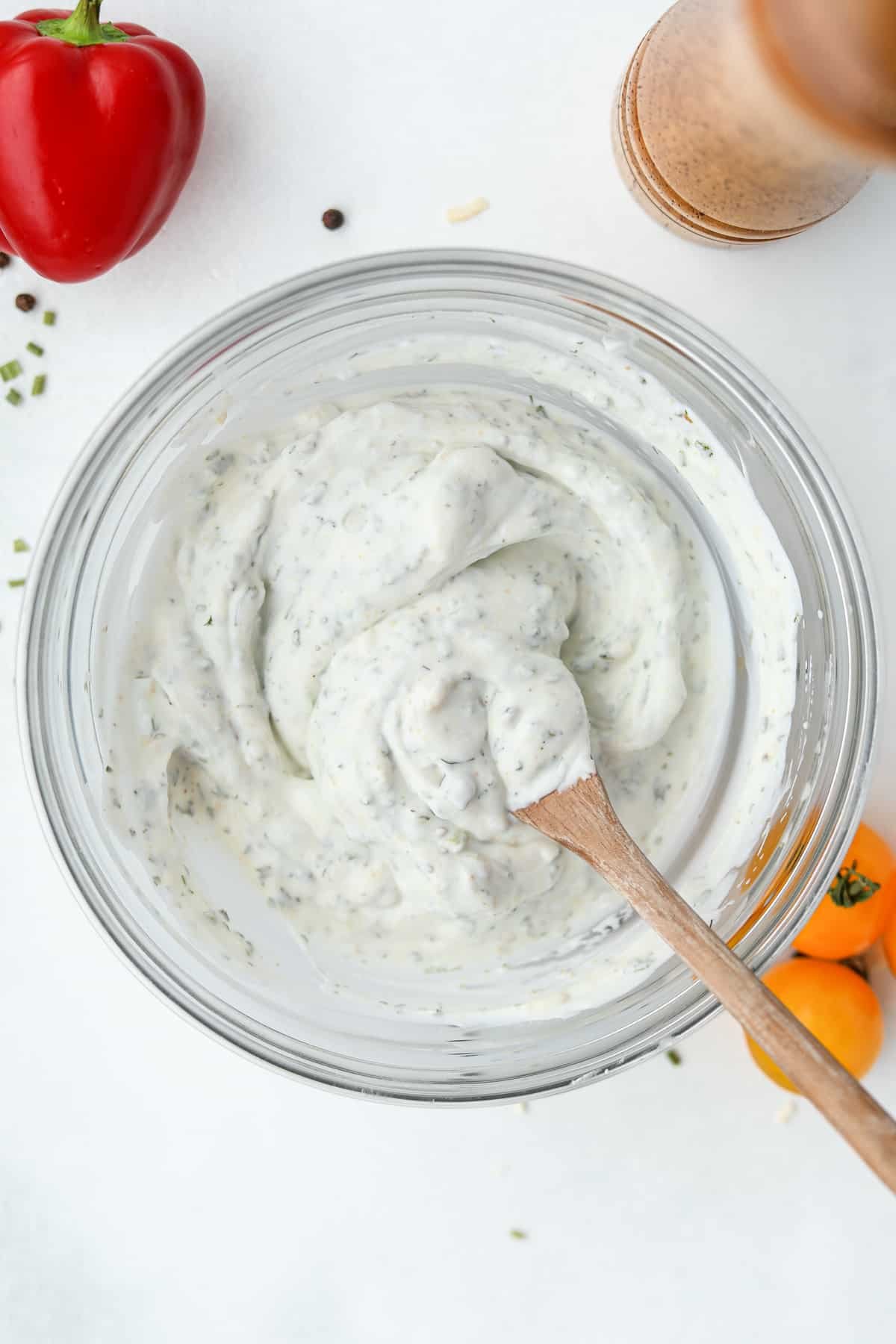 A bowl of homemade salad dressing that's being stirred with a wooden spoon.