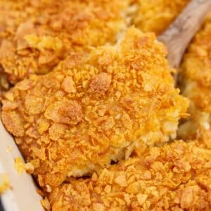 Lifting a square of hash brown casserole from a baking dish.