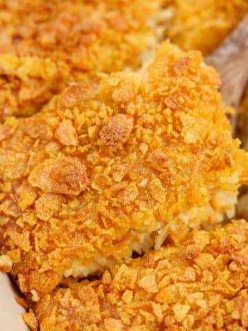 Lifting a square of hash brown casserole from a baking dish.