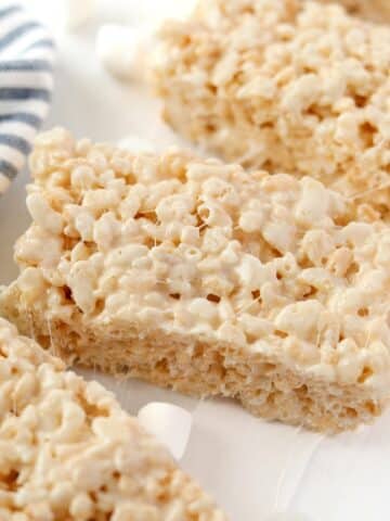 Homemade rice krispies treats on a white background with a blue stripe napkin.