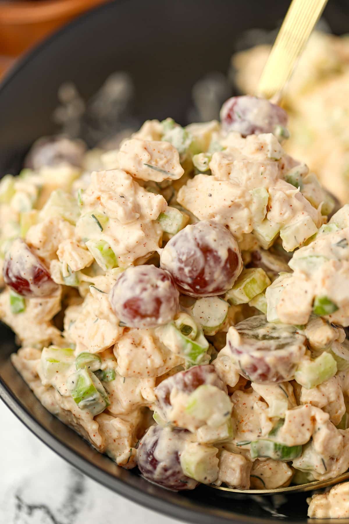 A close up of chicken salad dotted with red grapes.