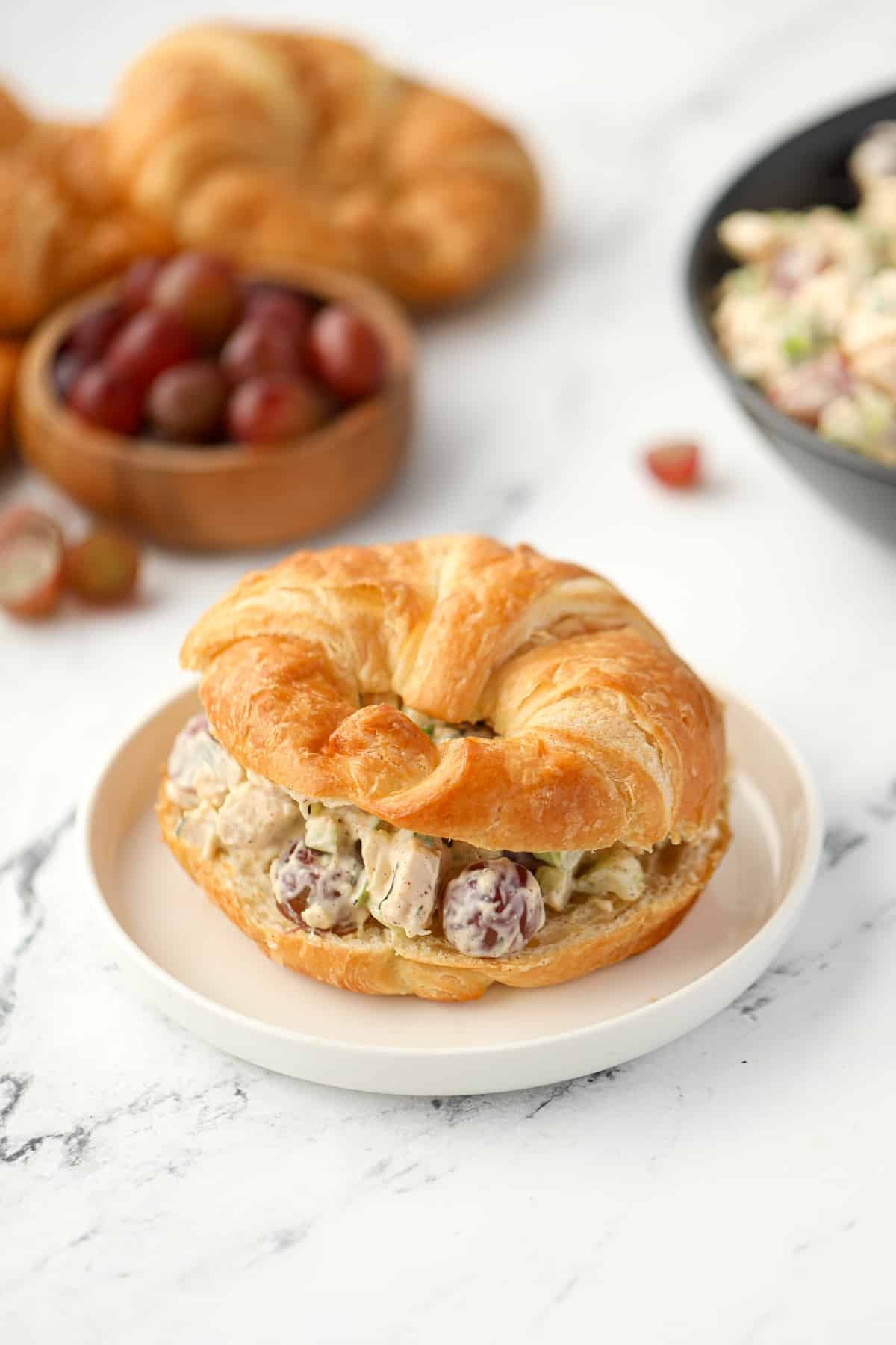 A croissant sliced in half and filled with chicken salad.