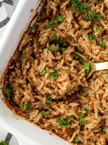 Scooping rice from a baking dish.